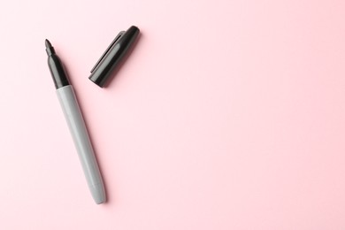 Photo of One black marker on light pink background, top view. Space for text