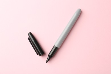 Photo of One black marker on light pink background, top view