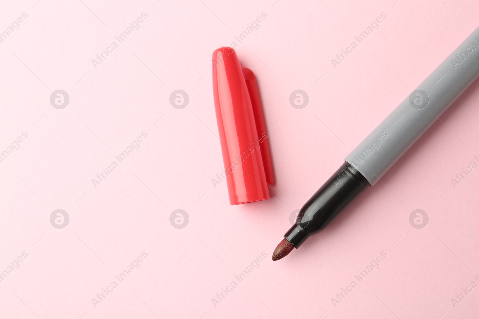 One red marker on light pink background, top view. Space for text Photo of One red marker on light pink background, top view. Space for text
