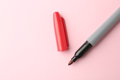 Photo of One red marker on light pink background, top view. Space for text
