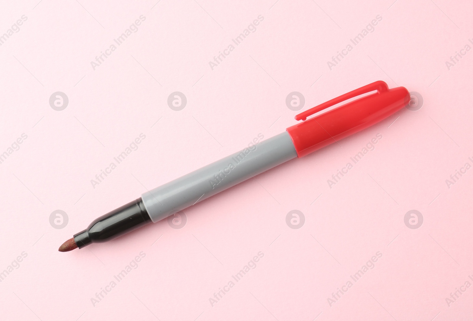 One red marker on light pink background, top view. Space for text Photo of One red marker on light pink background, top view. Space for text
