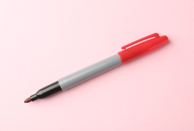 Photo of One red marker on light pink background, top view. Space for text