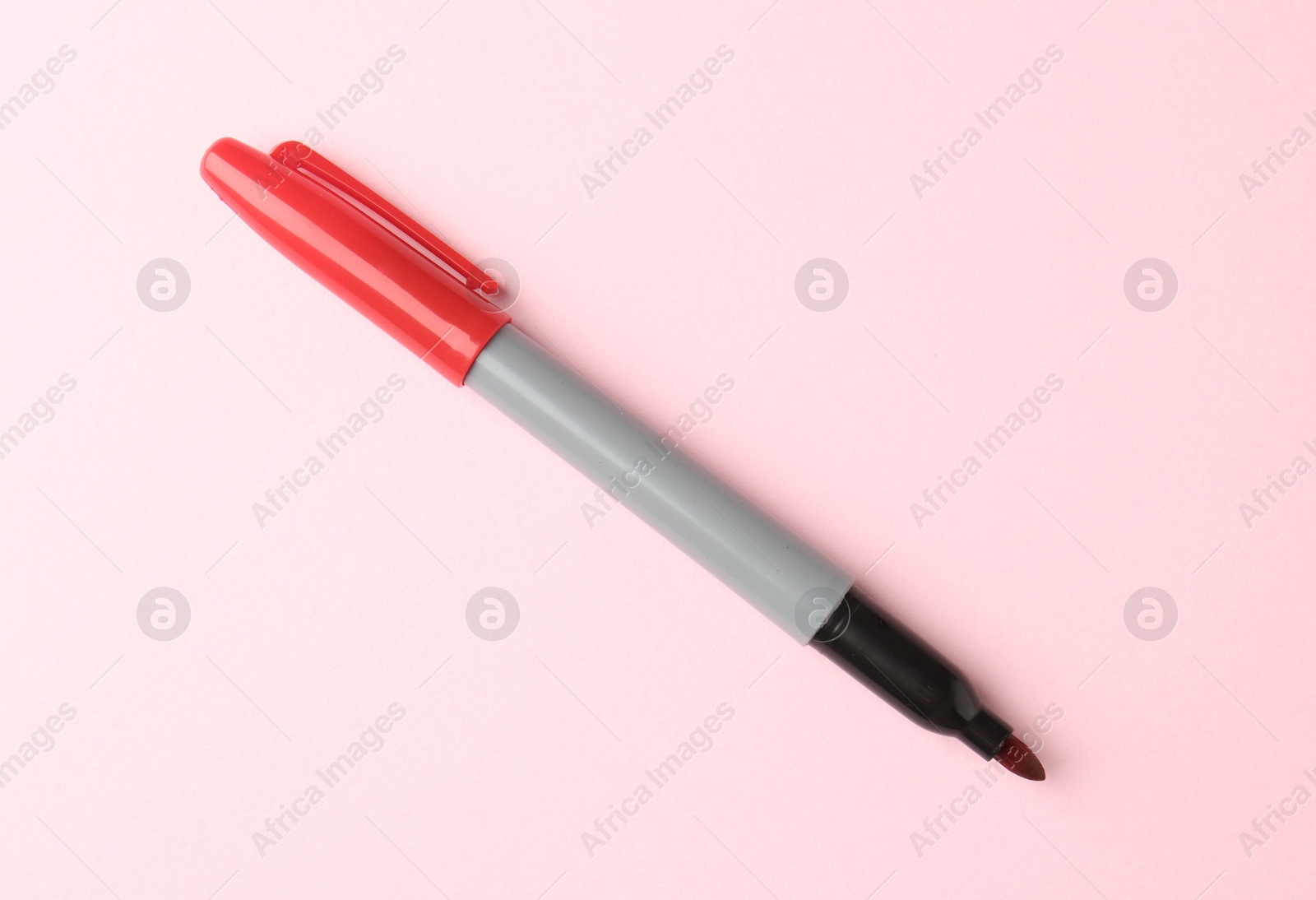 One red marker on light pink background, top view. Space for text Photo of One red marker on light pink background, top view. Space for text
