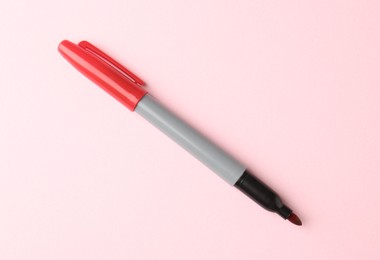 Photo of One red marker on light pink background, top view. Space for text