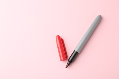 Photo of One red marker on light pink background, top view. Space for text