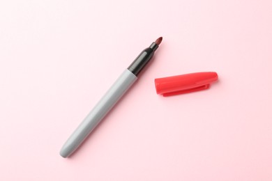 Photo of One red marker on light pink background, top view