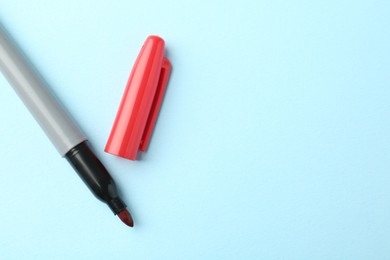 Photo of One red marker on light blue background, top view. Space for text