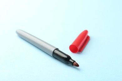 Photo of One red marker on light blue background, closeup