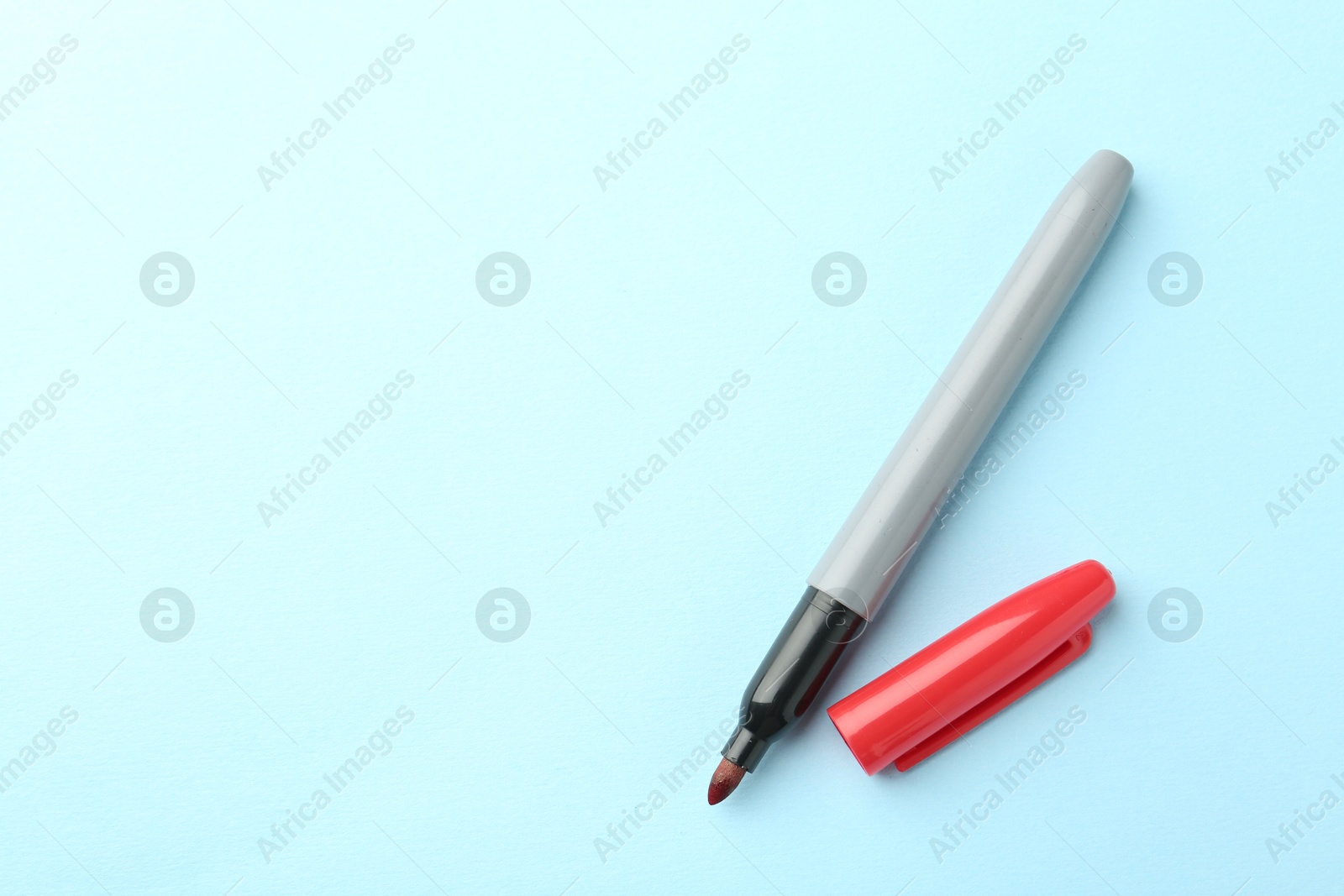 One red marker on light blue background, top view. Space for text Photo of One red marker on light blue background, top view. Space for text