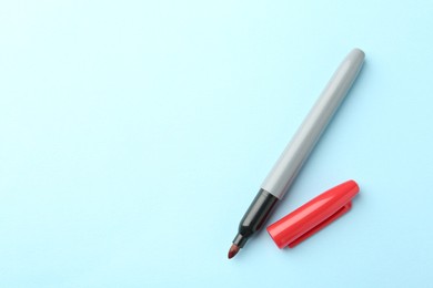 Photo of One red marker on light blue background, top view. Space for text