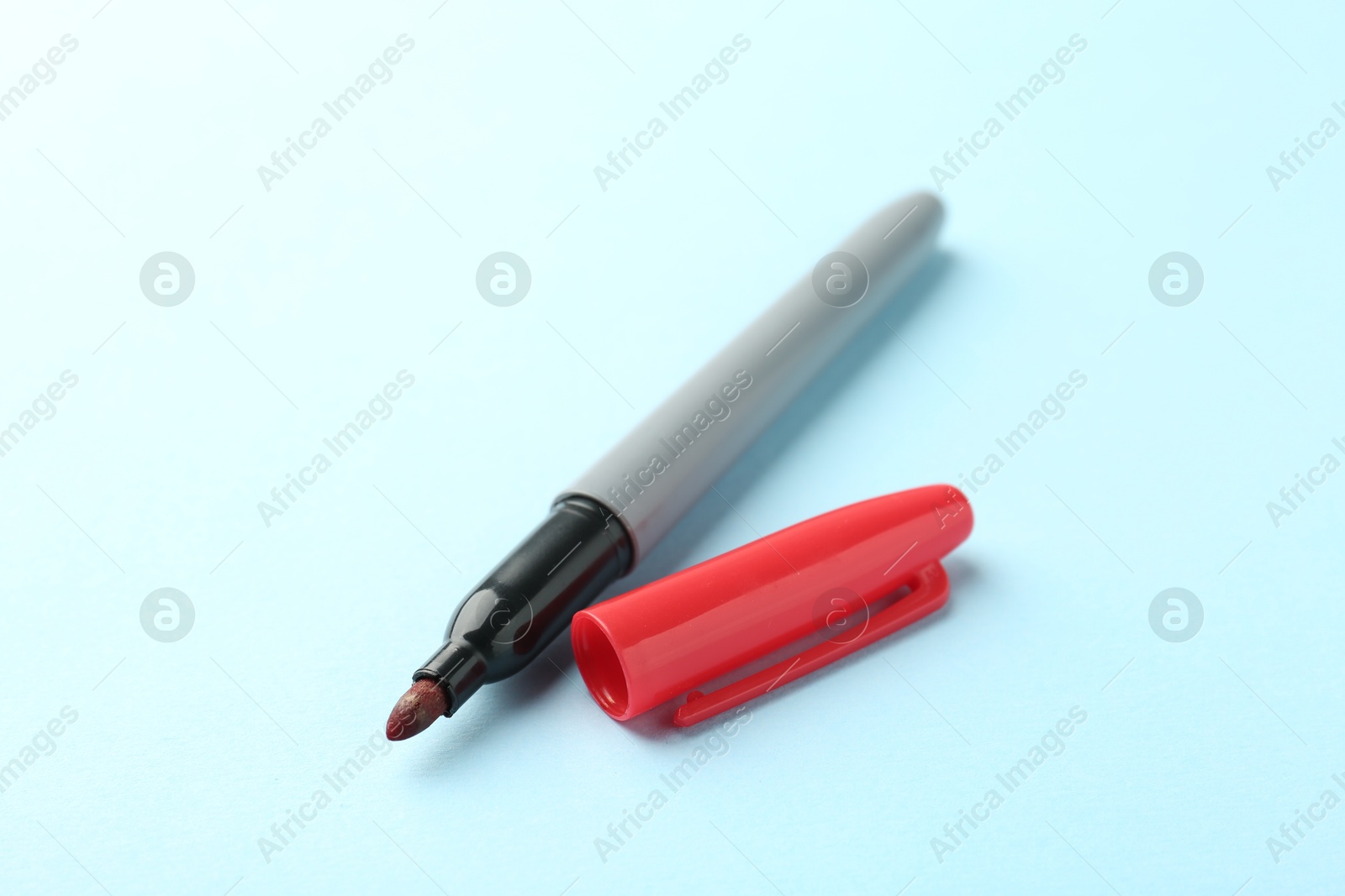One red marker on light blue background, closeup. Space for text Photo of One red marker on light blue background, closeup. Space for text