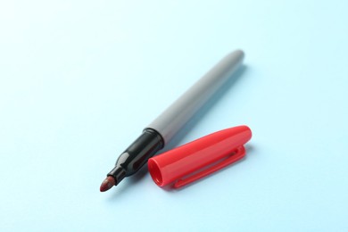 Photo of One red marker on light blue background, closeup. Space for text