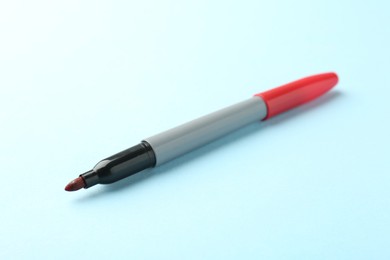 Photo of One red marker on light blue background, closeup. Space for text