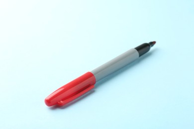 Photo of One red marker on light blue background, closeup. Space for text
