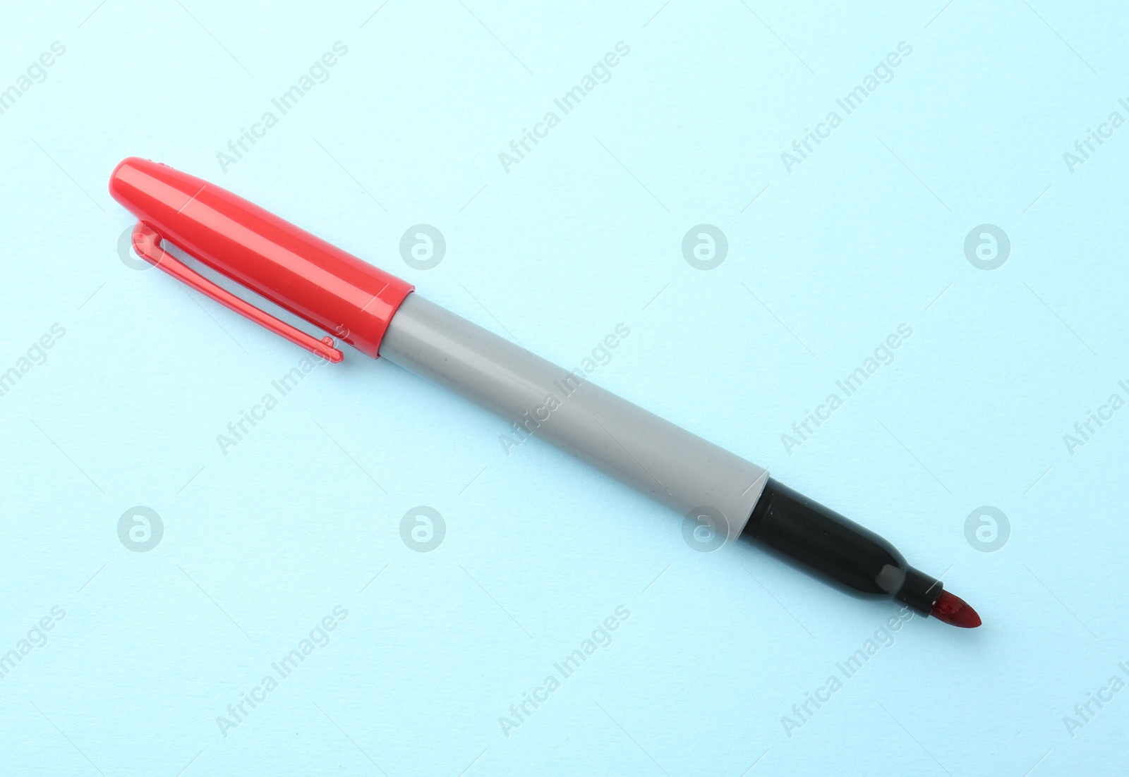 One red marker on light blue background, top view. Space for text Photo of One red marker on light blue background, top view. Space for text