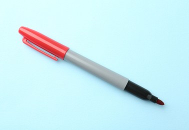 Photo of One red marker on light blue background, top view. Space for text