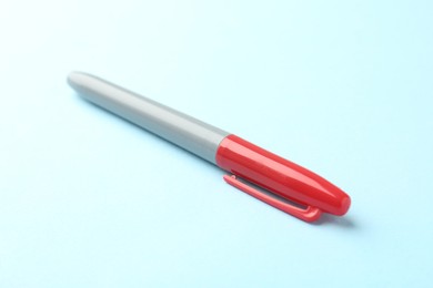 Photo of One red marker on light blue background, closeup