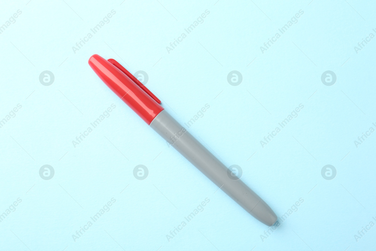 One red marker on light blue background, top view Photo of One red marker on light blue background, top view