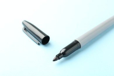 Photo of One black marker on light blue background, closeup
