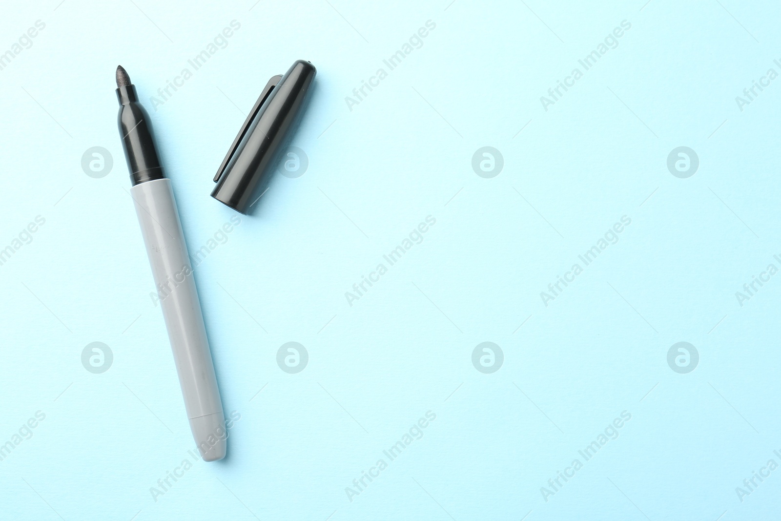 One black marker on light blue background, top view. Space for text Photo of One black marker on light blue background, top view. Space for text