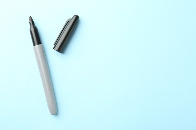 Photo of One black marker on light blue background, top view. Space for text