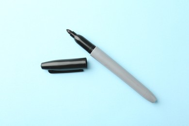 Photo of One black marker on light blue background, top view