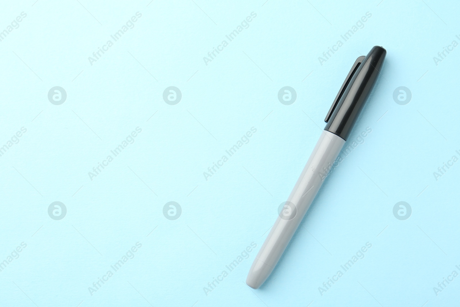 One black marker on light blue background, top view. Space for text Photo of One black marker on light blue background, top view. Space for text
