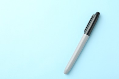 Photo of One black marker on light blue background, top view. Space for text