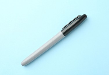 Photo of One black marker on light blue background, top view. Space for text