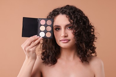 Photo of Woman with eyeshadow palette on beige background