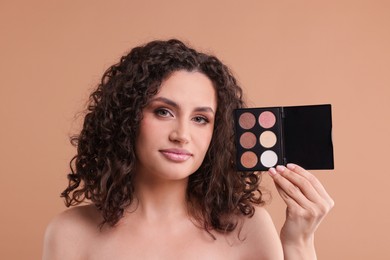 Photo of Woman with eyeshadow palette on beige background