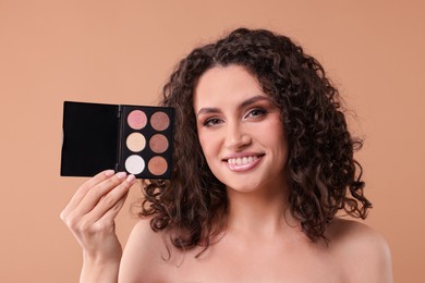 Photo of Smiling woman with eyeshadow palette on beige background