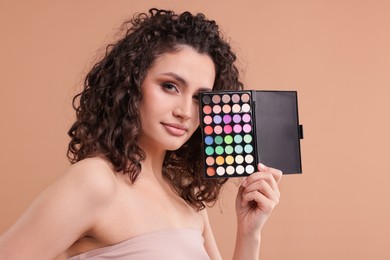 Photo of Woman with eyeshadow palette on beige background