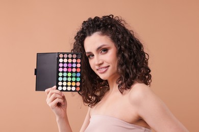 Photo of Smiling woman with eyeshadow palette on beige background