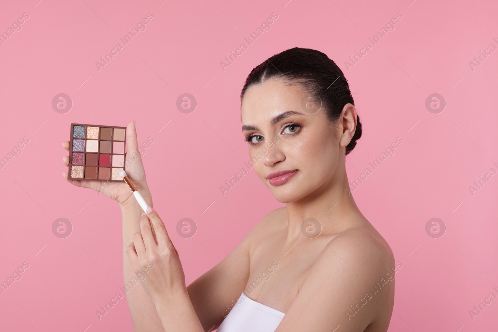 Woman with eyeshadow palette and brush on pink background Photo of Woman with eyeshadow palette and brush on pink background