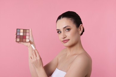 Photo of Woman with eyeshadow palette and brush on pink background