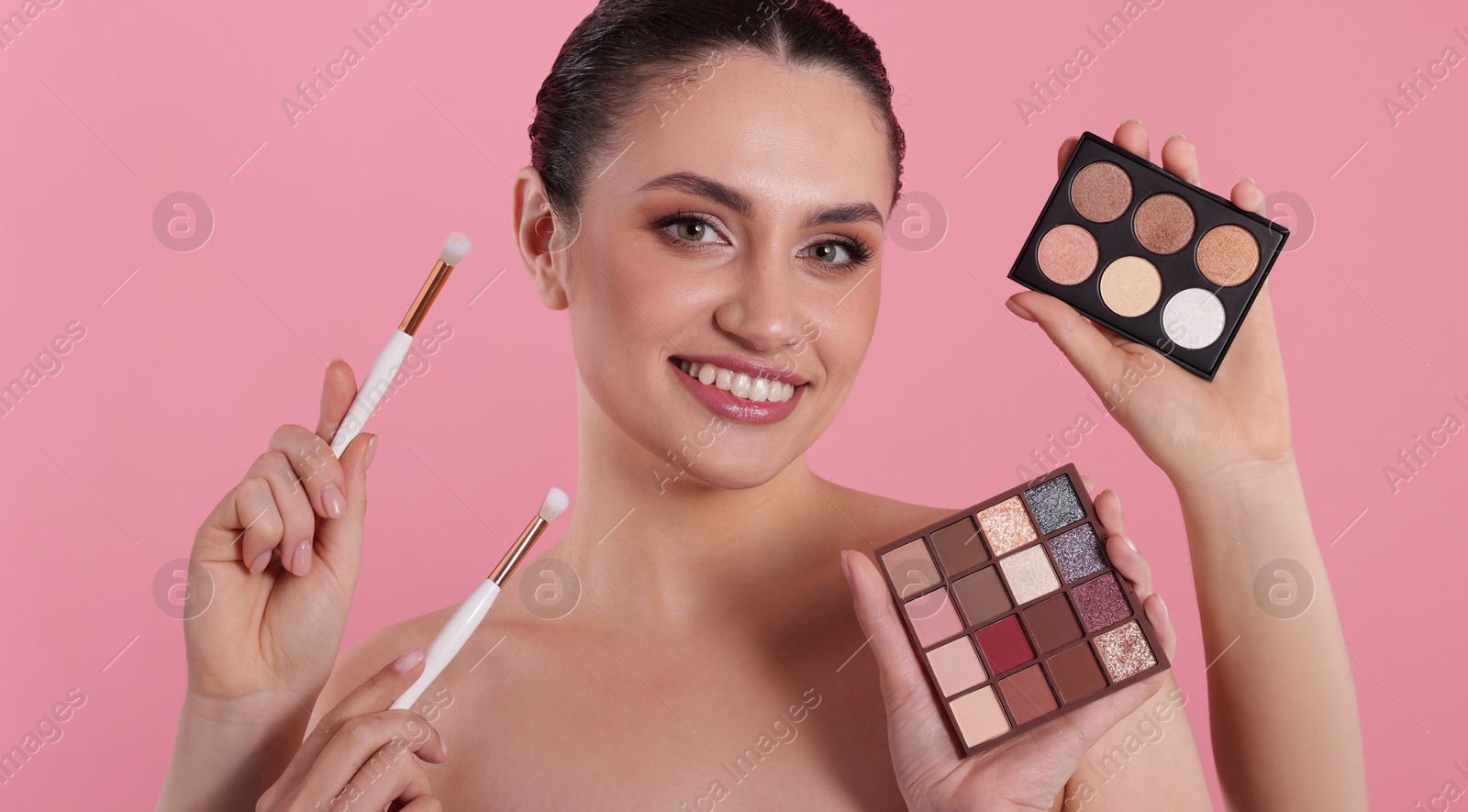 Makeup artist with eyeshadow palettes, brushes and smiling woman on pink background, closeup Photo of Makeup artist with eyeshadow palettes, brushes and smiling woman on pink background, closeup