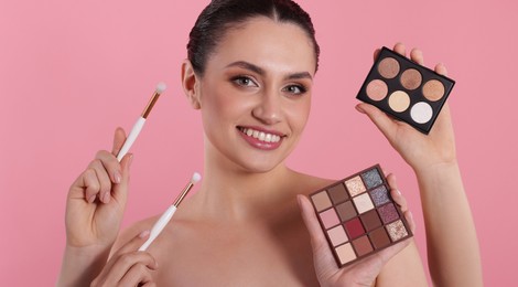 Photo of Makeup artist with eyeshadow palettes, brushes and smiling woman on pink background, closeup