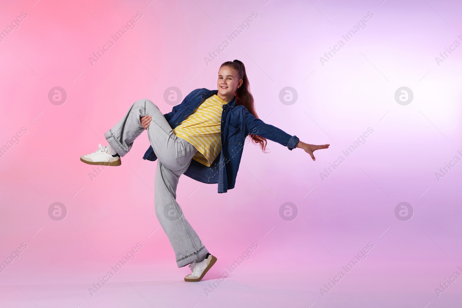 Photo of Girl in stylish clothes dancing on color background