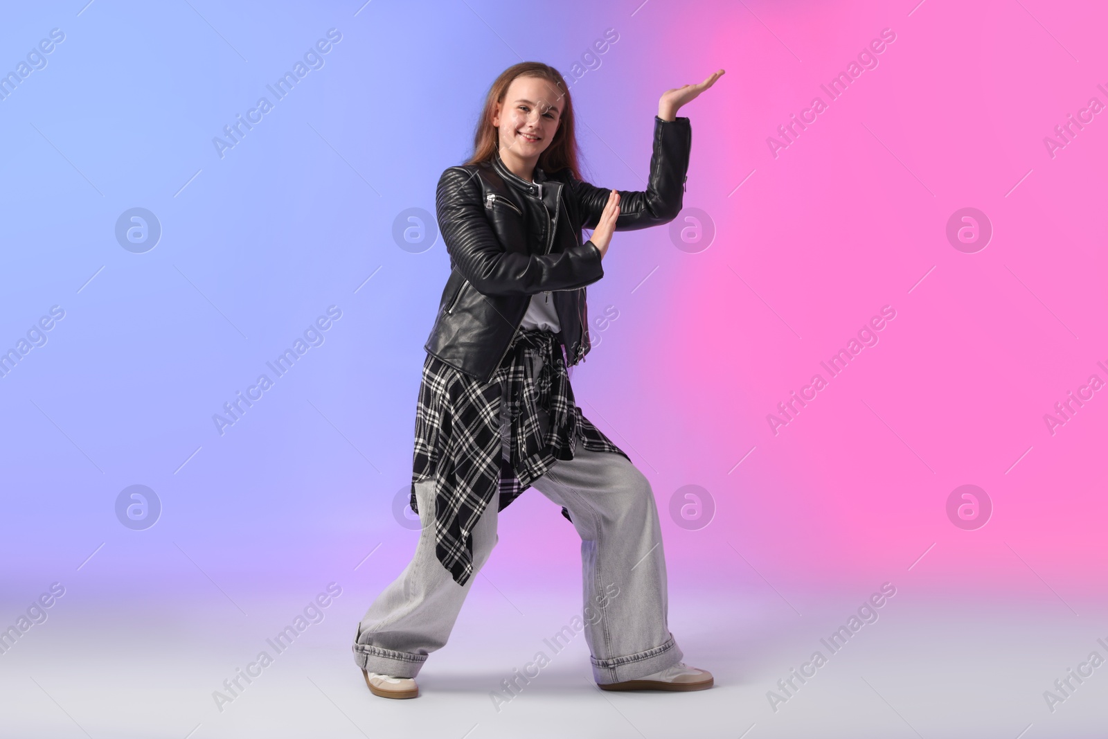 Photo of Girl in stylish clothes dancing on color background