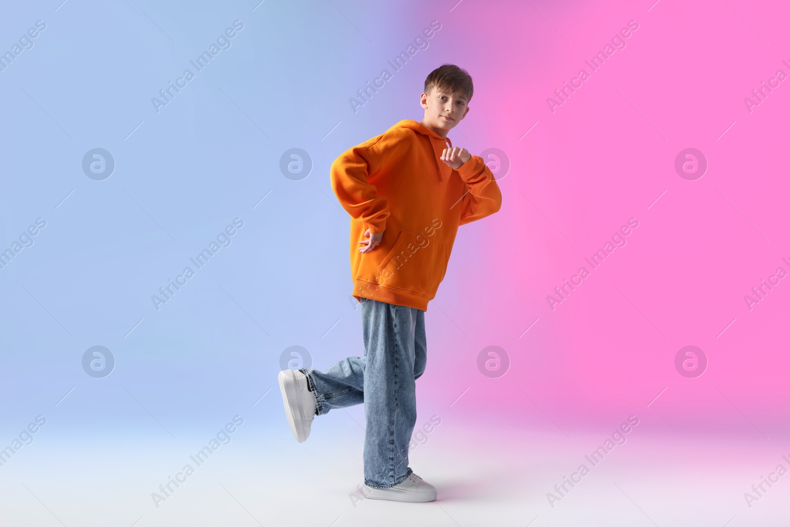 Photo of Boy in stylish clothes dancing on color background