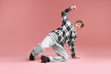 Photo of Boy with headphones in stylish clothes dancing on pink background
