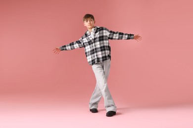 Photo of Boy with headphones in stylish clothes dancing on pink background