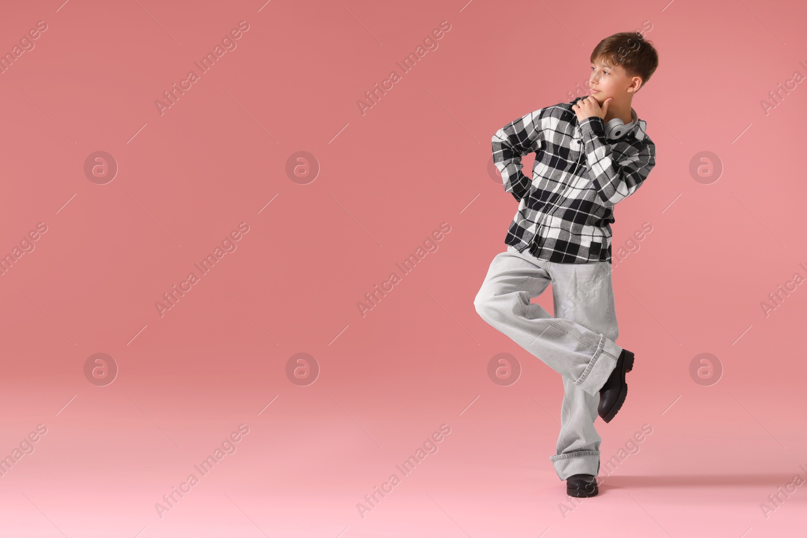 Boy with headphones in stylish clothes dancing on pink background, space for text Photo of Boy with headphones in stylish clothes dancing on pink background, space for text