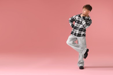 Photo of Boy with headphones in stylish clothes dancing on pink background, space for text