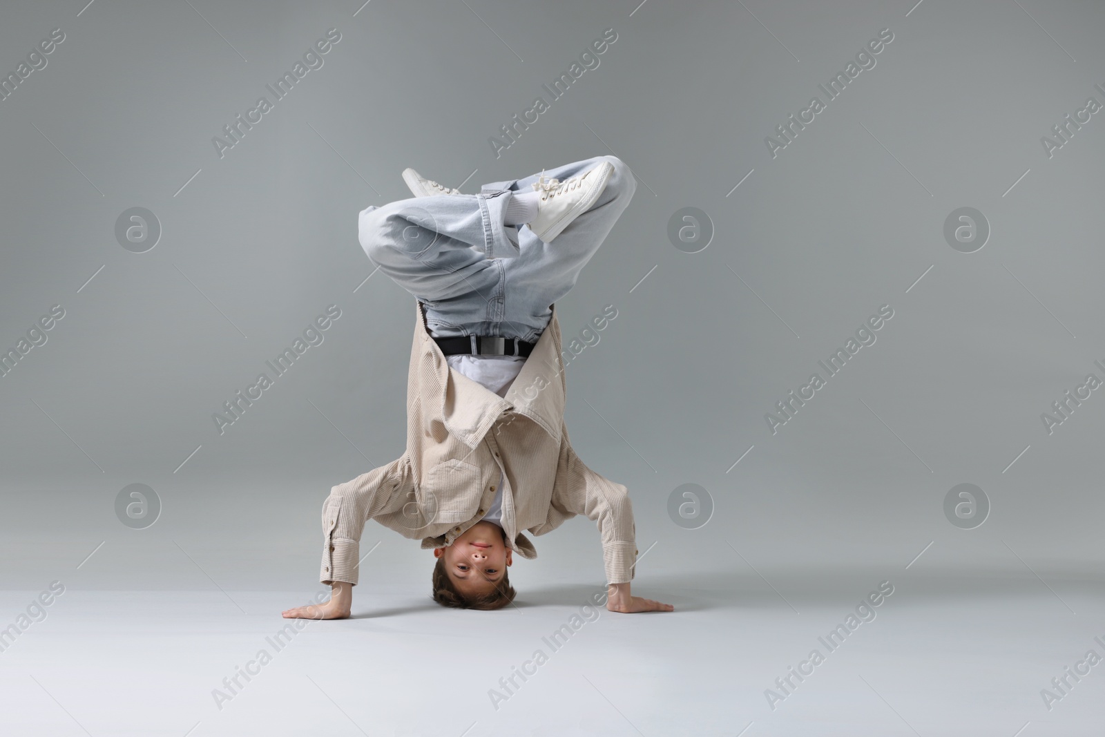 Photo of Boy in stylish clothes dancing on light grey background, space for text