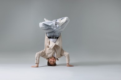Photo of Boy in stylish clothes dancing on light grey background, space for text