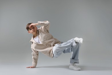 Photo of Boy in stylish clothes dancing on light grey background