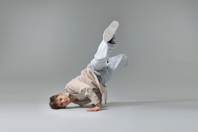 Photo of Boy in stylish clothes dancing on light grey background
