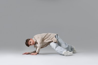 Photo of Boy in stylish clothes dancing on light grey background